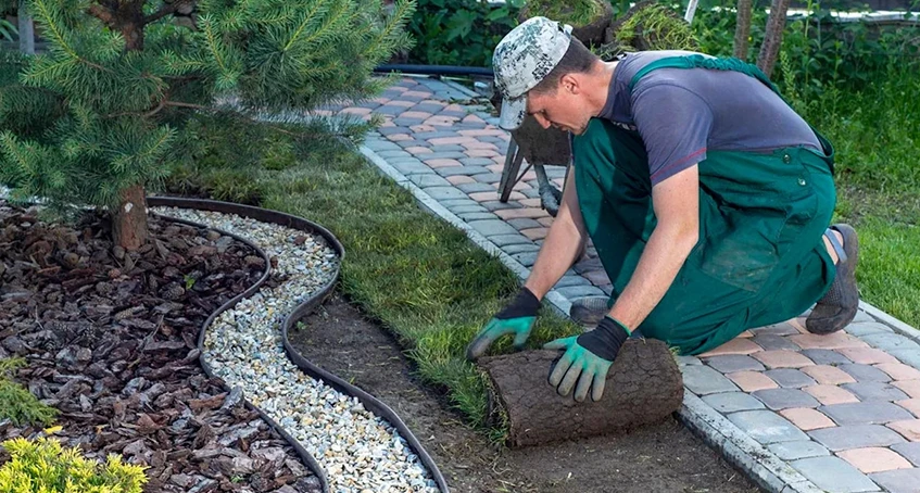 Gardener Laying Sod Beside Patio with Stone Pathway