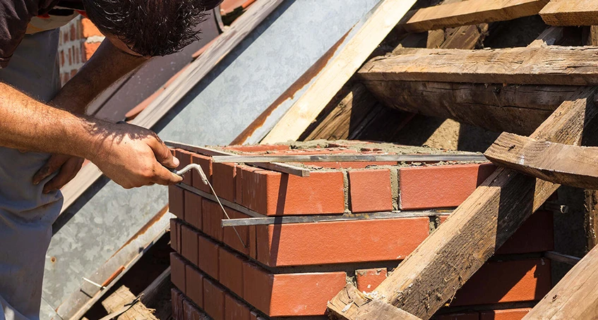Worker Constructing Brick Retaining Wall with Trowel