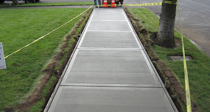 Freshly Poured Concrete Construction Sidewalk with Safety Cones and Caution Tape